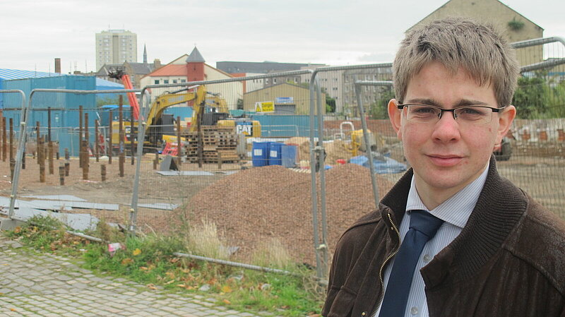 Jack Caldwell standing in front of a fenced-off building site in Bonnington.