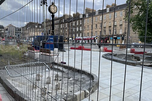 Elm Row's clock behind some heras fencing in early 2023