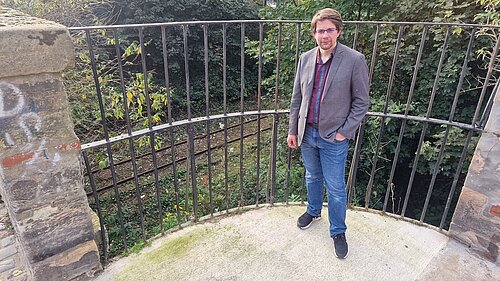Cllr Jack Caldwell standing in front of railings and the railway line