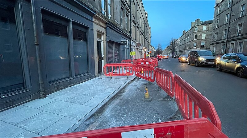 Barriers and a new pavement in the foreground of Albert Place during dusk