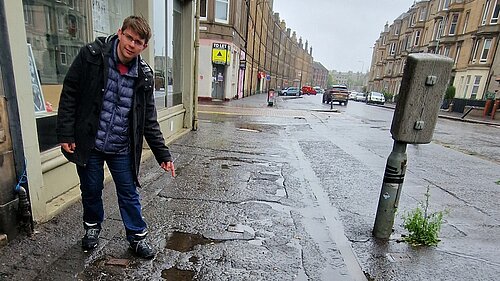 Jack pointing at broken pavements on Easter Road
