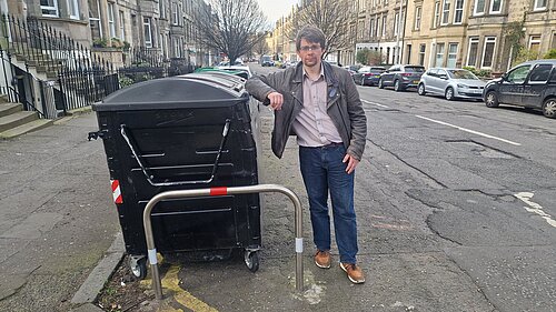 Jack standing next to a set of communal bins