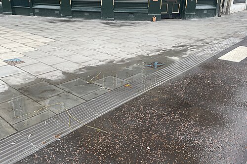 Water flooding out of an access hatch onto a pavement