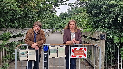 Jack and Sanne behind a fence with a sign saying "Bridge Closed"