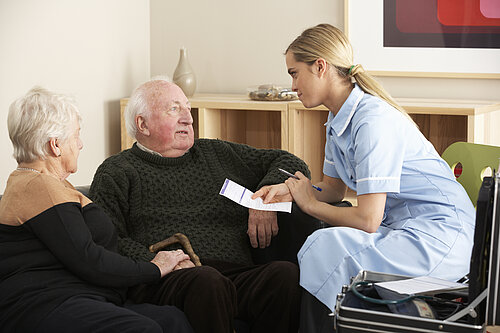 A medical professional attends to an elderly couple at their home