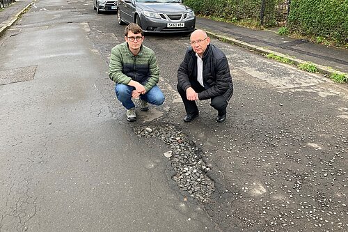 councillors pointing at potholes
