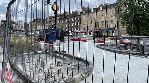 Elm Row's clock behind some heras fencing in early 2023