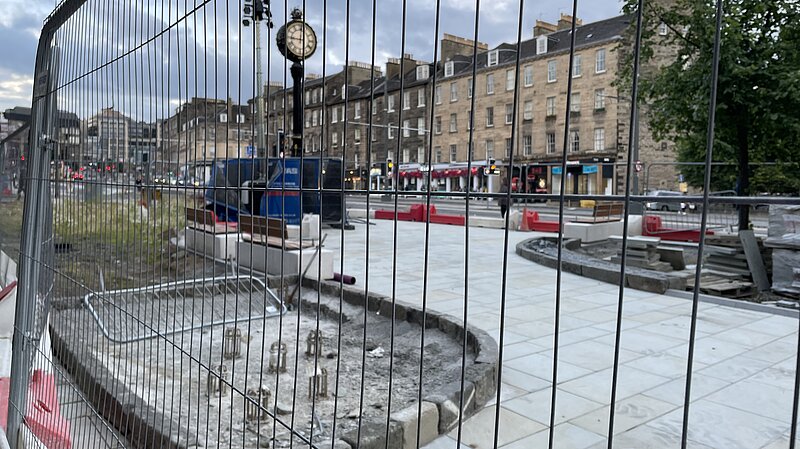 Elm Row's clock behind some heras fencing in early 2023