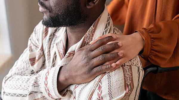 A carer holding the hand of another person