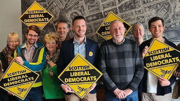Mike Andersen with a group of activists behind him holding Lib Dem diamonds
