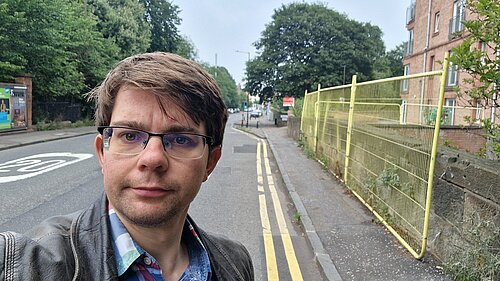 Jack standing in front of yellow fencing and a narrow pavement