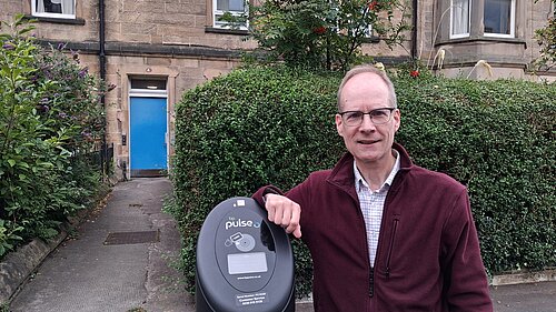 Councillor Neil Ross standing next to an EV charger